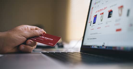 Photo of a hand with a credit card next to computer monitor Photo of a hand with a credit card next to computer monitor