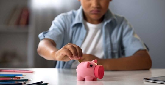 Child Putting Money in Piggy Bank Child Putting Money in Piggy Bank