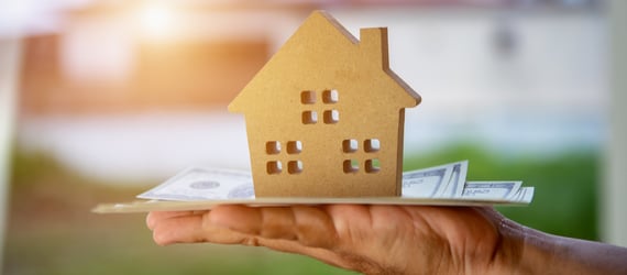 Photo of a hand holding money a small wooden house. Photo of a hand holding money a small wooden house.