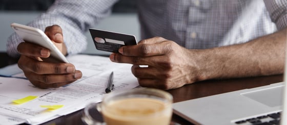 Photo of a man holding a phone and a credit card. Photo of a man holding a phone and a credit card.