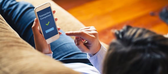Photo of a woman completing a transaction on her phone. Photo of a woman completing a transaction on her phone.