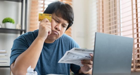 Worried man holding a credit card looking at the bill Worried man holding a credit card looking at the bill