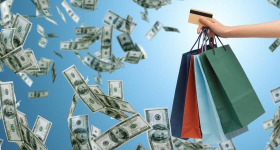 Close up of a hand holding shopping bags and a credit card over blue background and money rain Close up of a hand holding shopping bags and a credit card over blue background and money rain