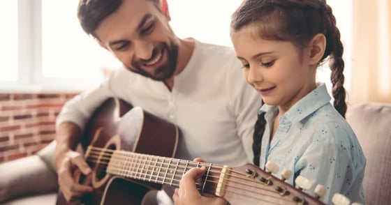 Man teaching little girl how to play the guitar Man teaching little girl how to play the guitar