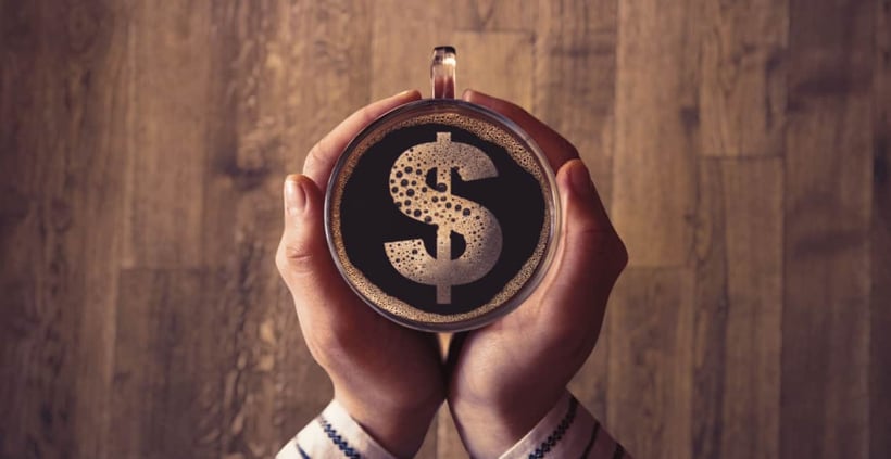 hands holding a coffee mug with dollar sign in it