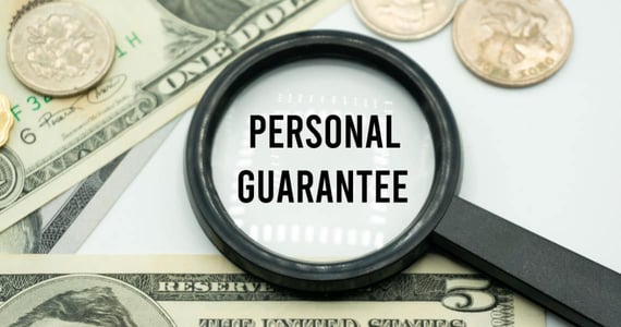 Magnifying glass showing the words "Personal Guarantee" placed on background of banknotes and coins Magnifying glass showing the words "Personal Guarantee" placed on background of banknotes and coins
