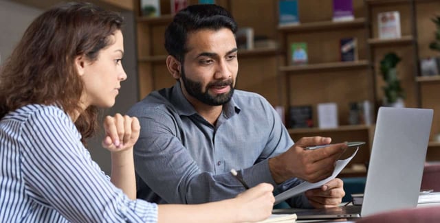 A man and a woman sitting in front of a laptop having a discussion. A man and a woman sitting in front of a laptop having a discussion.