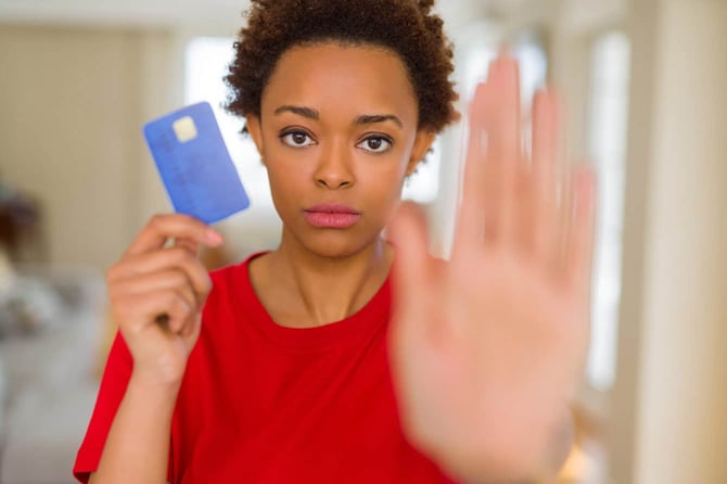 Young African American woman holding a credit card with open hand doing stop sign with serious and confident expression Young African American woman holding a credit card with open hand doing stop sign with serious and confident expression