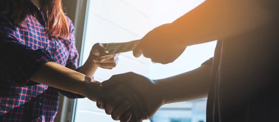 Two people exchanging cash and shaking hands Two people exchanging cash and shaking hands