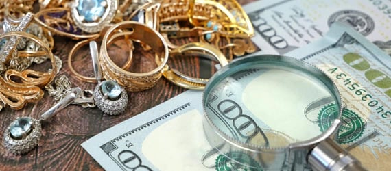Money, jewelry, and a magnifying glass laying on a wood table Money, jewelry, and a magnifying glass laying on a wood table