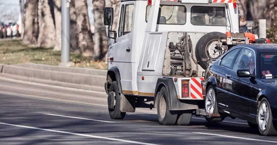 Black car being towed away by a white truck Black car being towed away by a white truck