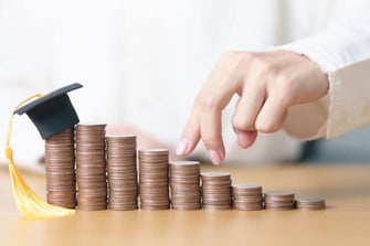 a person counting pennies with a grad cap