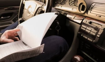 a person in a car reviewing documents graphic
