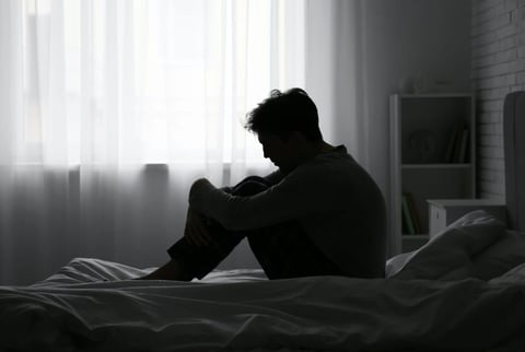 a man sitting on his bed in a dark room graphic a man sitting on his bed in a dark room graphic