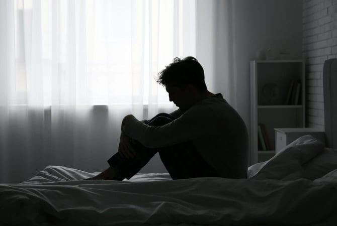 a man sitting on his bed in a dark room graphic a man sitting on his bed in a dark room graphic