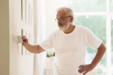 Senior man adjusting thermostat Senior man adjusting thermostat