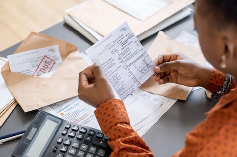 Over-the-shoulder shot of woman checking bills Over-the-shoulder shot of woman checking bills